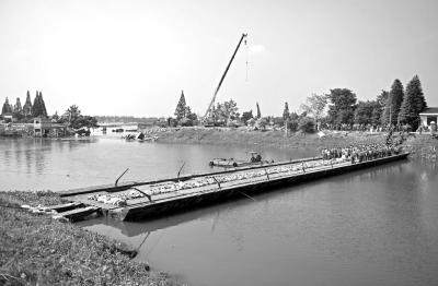 11日,湖南華容新華垸潰口附近已搭起浮橋,潰口兩側挖掘機、卡車輪番作業(yè)進行填堵,潰口正逐漸縮小。